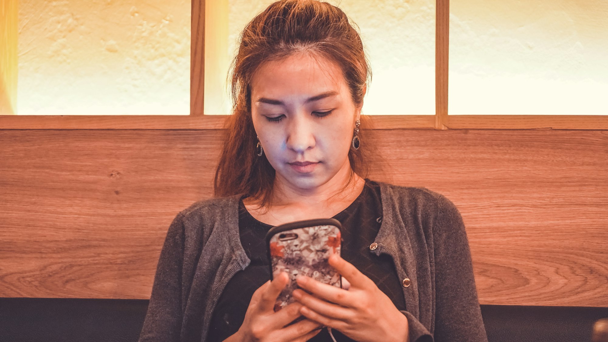 Portrait of a smiling casual woman holding smartphone in the restaurant.